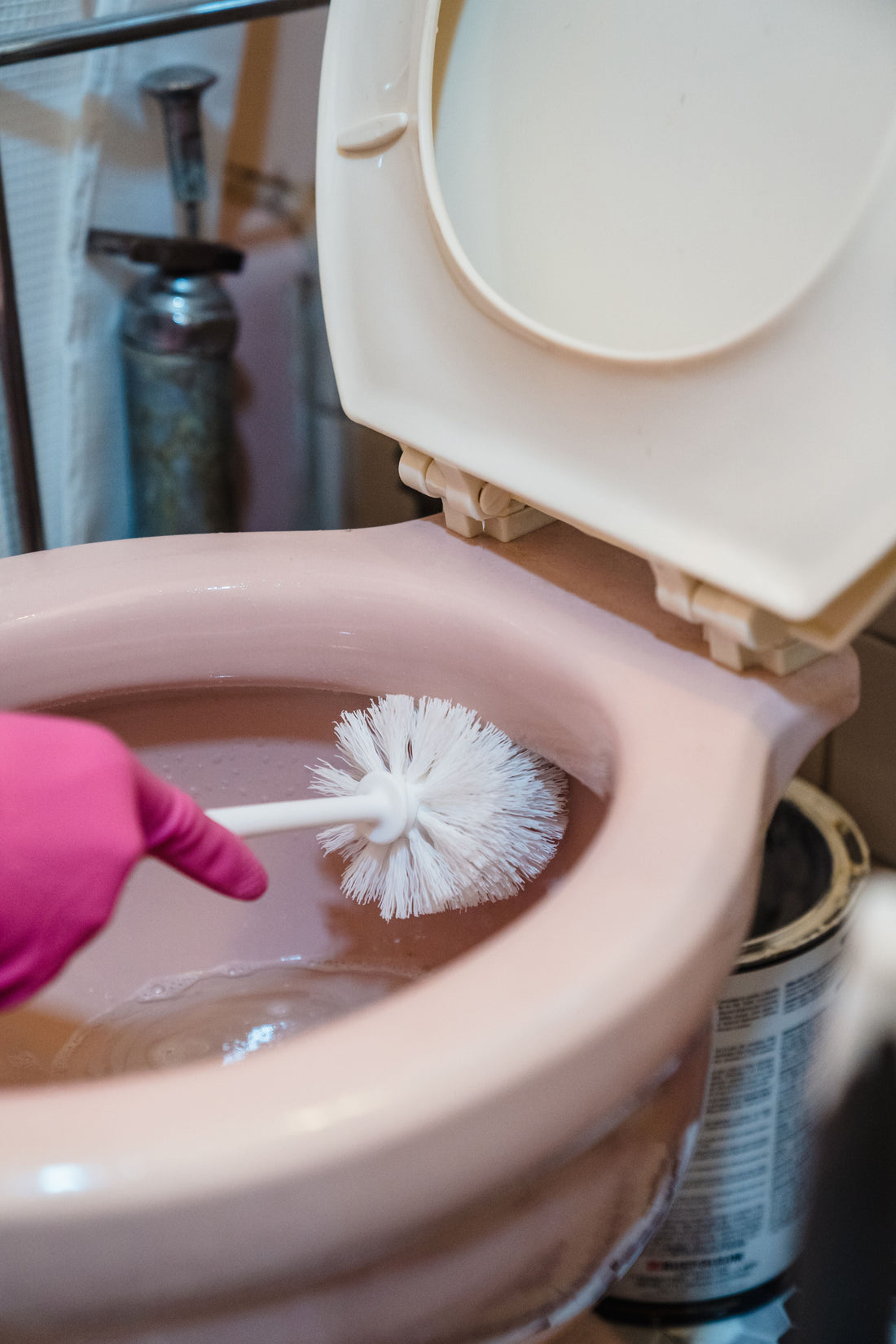 Person cleaning a toilet bowl with a brush